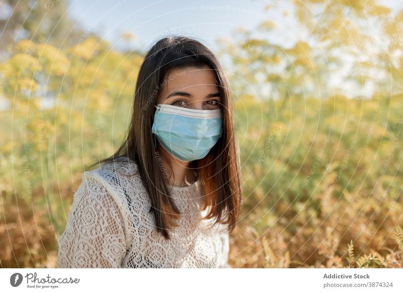 Frau mit medizinischer Maske im Feld Mundschutz Coronavirus neue Normale Natur behüten verhindern sonnig Sicherheit Windstille COVID ansteckend viral Gefahr