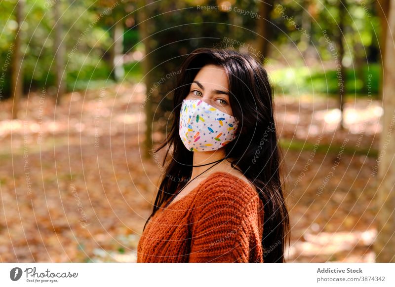 Junge Frau mit Schutzmaske im Park Mundschutz Coronavirus behüten Bund 19 COVID19 Infektion verhindern Porträt Pandemie Stoff Textil selbstbewusst jung brünett