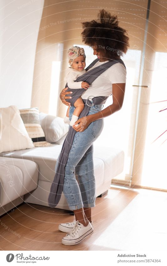 Schwarze Frau mit Baby in der Trage zu Hause Träger Babytragetuch Mutter Kleinkind heimwärts Eltern Pflege Angebot bezaubernd ethnisch schwarz Afroamerikaner
