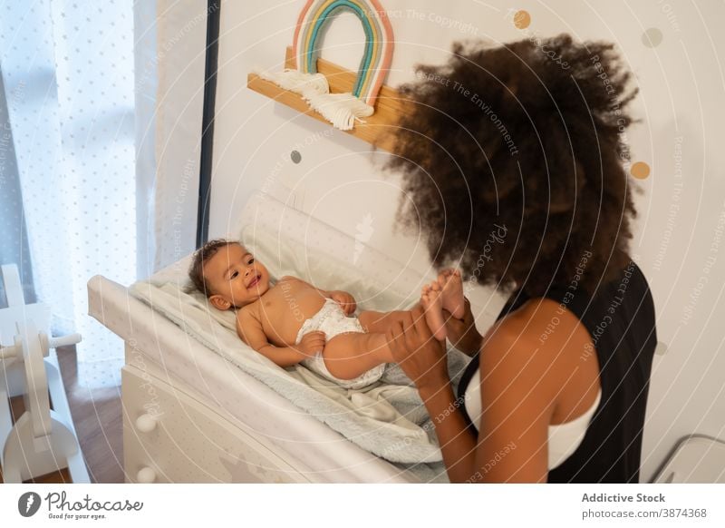 Schwarze Frau spielt mit niedlichen Baby auf Wickeltisch Wandel & Veränderung Tisch Windel Mutter Angebot spielerisch Kleinkind Windeln Pflege ethnisch schwarz