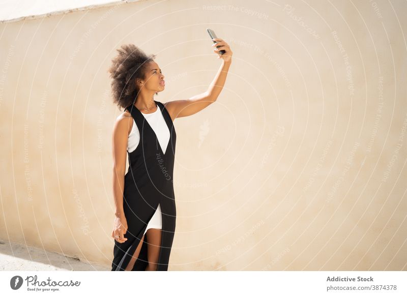 Ethnische Frau steht auf der Straße mit Smartphone sorgenfrei Selfie ethnisch schwarz Afroamerikaner Apparatur Gerät Mobile Dame sich[Akk] entspannen ruhen