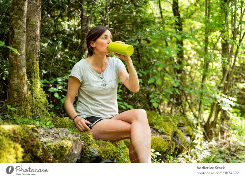 Reisende Frau trinkt Wasser im Wald trinken Reisender Trekking sich[Akk] entspannen Wälder Entdecker Tourist Pause Flasche frisch ruhen sitzen Stein Moos Sommer
