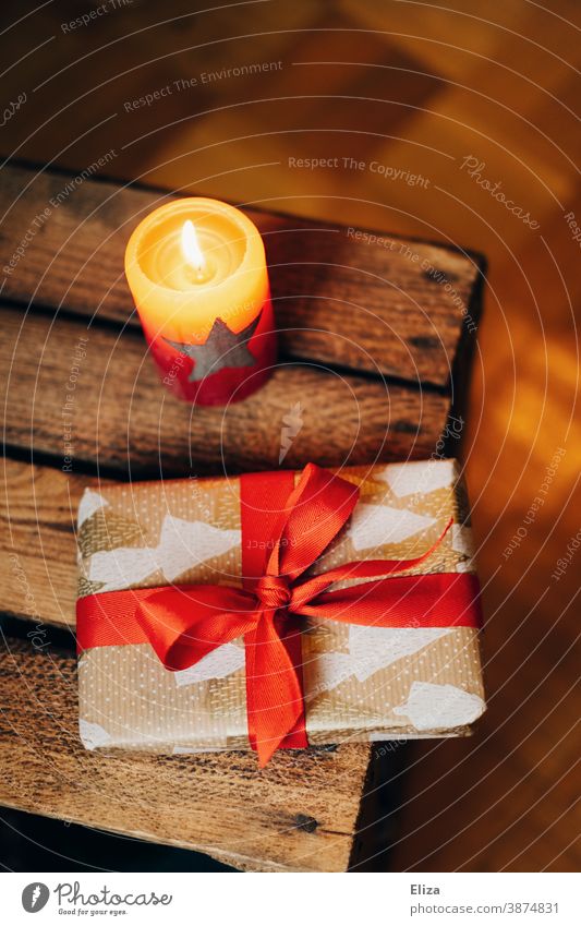 Weihnachtsgeschenk neben brennender Kerze Weihnachten Weihnachtsstimmung schenken Geschenk Kerzenschein brennende Kerze Weihnachten & Advent Überraschung rot