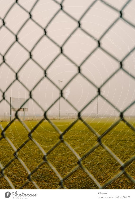 Menschenleeres Fußballfeld in Coronazeiten menschenleer fussballplatz training rasen wiese grün winter grau nebel zaun lock down corona coronavirus sport verbot