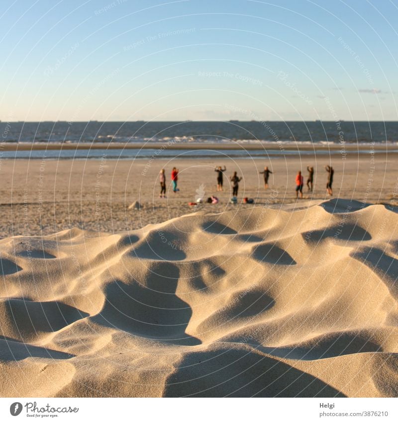 sportlich - hinter einer Sanddüne turnt eine Gymnastikgruppe am Strand der Nordsee Düne Nordseestrand Sport turnen Abendsonne Licht Schatten Wasser Meer