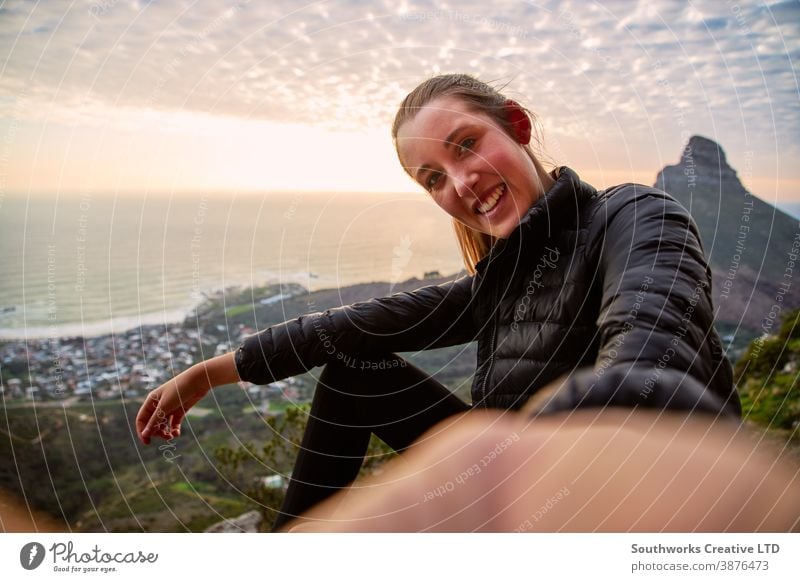 Junge Frau mit Rucksack wandert entlang des Küstenpfades und posiert für Social Media Selfie auf dem Handy fotografierend Influencer Sonnenuntergang