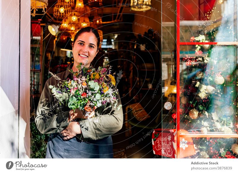 Frau mit Blumenstrauß steht vor einem Geschäft Feiertag Fenster Weihnachten Laden festlich Illumination Blumenhändler Blütezeit Straße Großstadt außerhalb