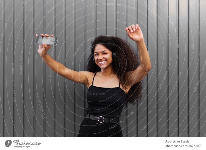 Glückliche ethnische Frau tanzt auf der Straße Tanzen Musik zuhören Kopfhörer fröhlich Spaß haben genießen sich[Akk] bewegen schwarz Afroamerikaner Freude Klang