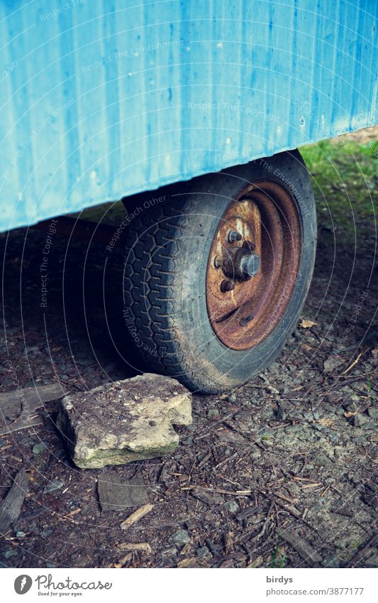 Rad eines alten Bauwagens mit einem Stein davor als wegrollschutz. Hemmschuh Sicherheit wegrollen Reifen rostig blockieren parken Standfestigkeit gesichert