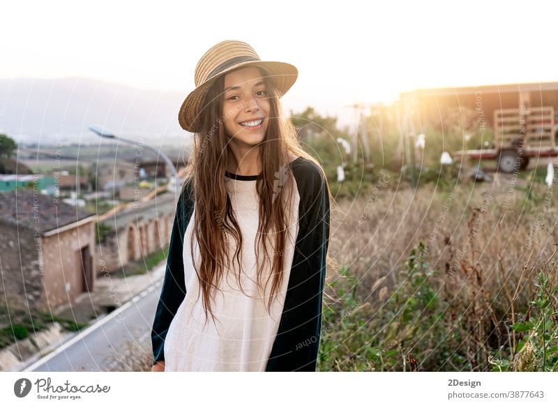 Junger lächelnder Teenager Reisende mit Sommerkleidung und Hut, der draußen vor der Kamera steht Glück Mädchen Stehen Lächeln in die Kamera schauen zahnfarben