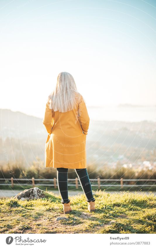 Frau im gelben Mantel sitzt auf einer Bank und betrachtet die Landschaft Winter Herbst betrachtend Vigo Galicia Natur im Freien Freiheit Sonnenuntergang