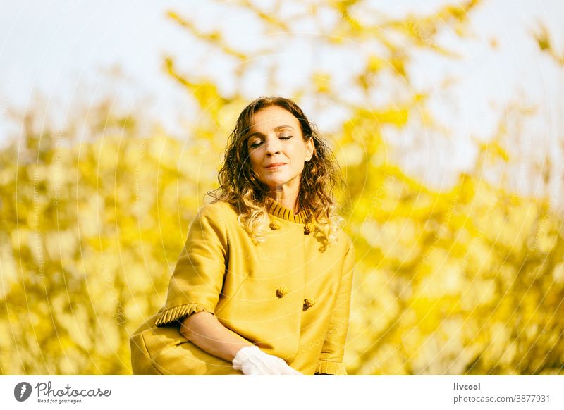 Frau, die sich im Herbst im Park ausruht retuschieren Behaarung Blätter gelb Garten Gelblich Lifestyle reif Porträt eine Person Baum Mantel gelber Überzieher