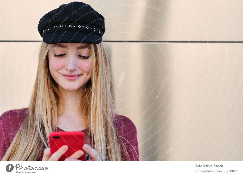 Trendy Millennial Frau in Kappe mit Smartphone benutzend trendy Stil Farbe rot Hut Telefon Hipster Browsen Teenager Schüler Herbst Outfit Mobile Apparatur Gerät