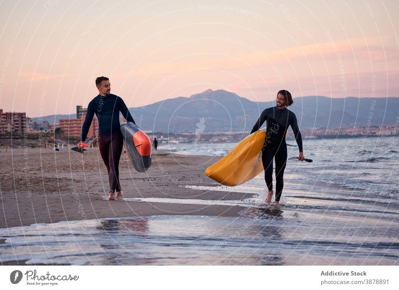 Männer mit Paddleboards gehen am Strand entlang Paddelbrett Surfer Spaziergang Holzplatte Surfbrett MEER Sonnenuntergang männlich Freund Freundschaft Meeresufer