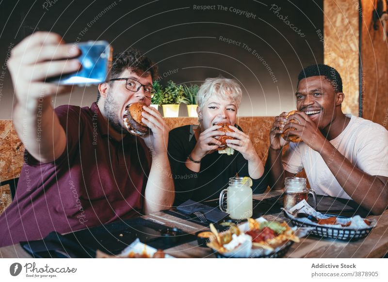 Gesellschaft von Freunden, die ein Selfie mit Burgern im Cafe machen essen Menschen Spaß haben Fastfood Junk Food Café heiter multiethnisch vielfältig