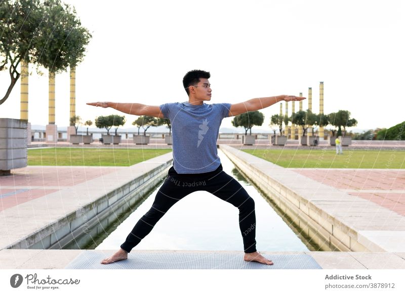 Mann macht Yoga in Krieger-Pose beweglich üben virabhadrasana Barfuß Unterlage Großstadt Dehnung männlich ethnisch asiatisch Asana Achtsamkeit Vitalität