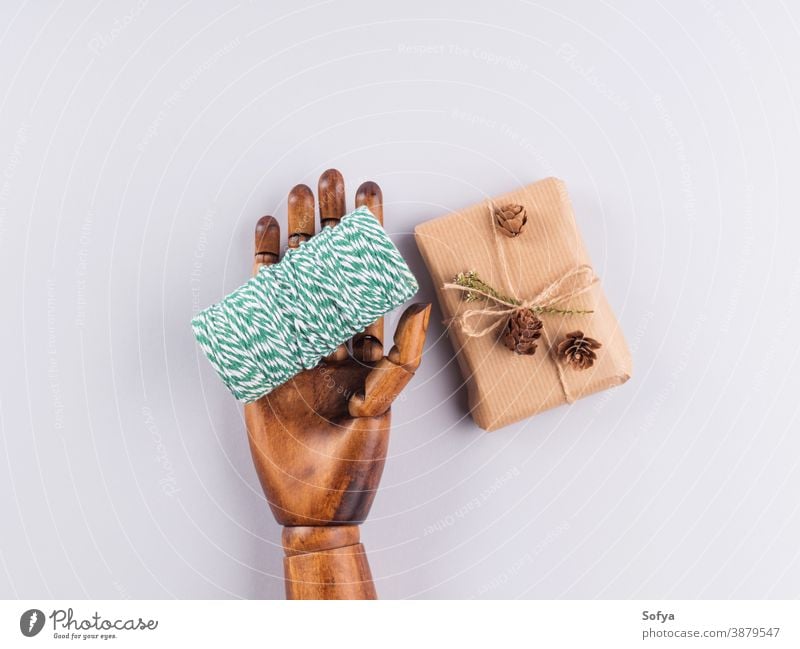 Grüner Weihnachtszwirn und Geschenkkarton in Holzhand Weihnachten Hintergrund keine Verschwendung grau Feiertag präsentieren Kasten Ornament Überraschung