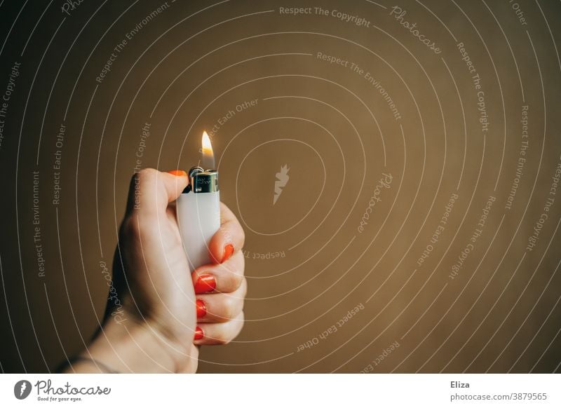 Eine weibliche Hand hält ein brennendes Feuerzeug anzünden zündend Licht Flamme heiß Nagellack entzünden zündeln Frauenhand Zünden Hintergrund neutral Wärme