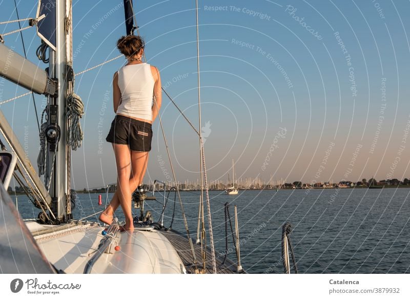An diesem Sommerabend steht die junge Frau  Backbord voraus und schaut auf die Marina am Horizont Segelyacht person weiblich stehen beobachren Mast Segeln