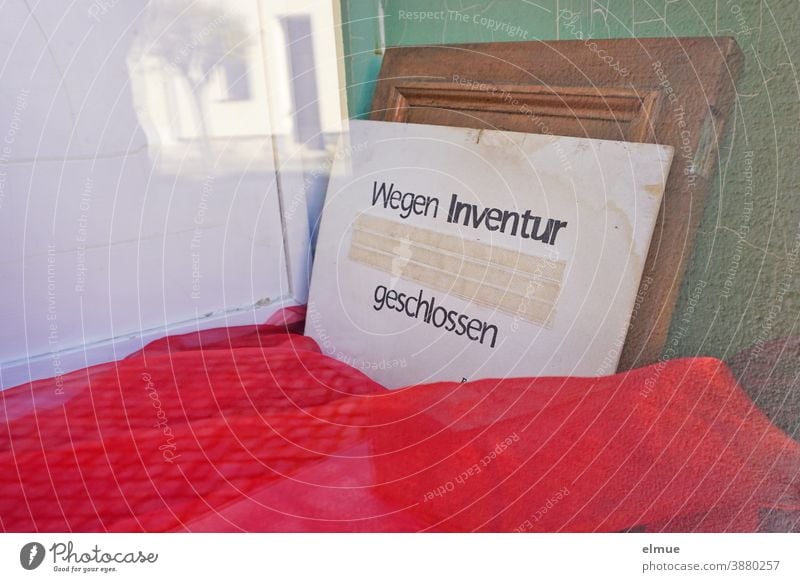 "Wegen Inventur geschlossen" steht auf einem an die Wand gelehnten Pappschild in der leeren, mit einem roten Stoff ausgelegten Schaufensterauslage