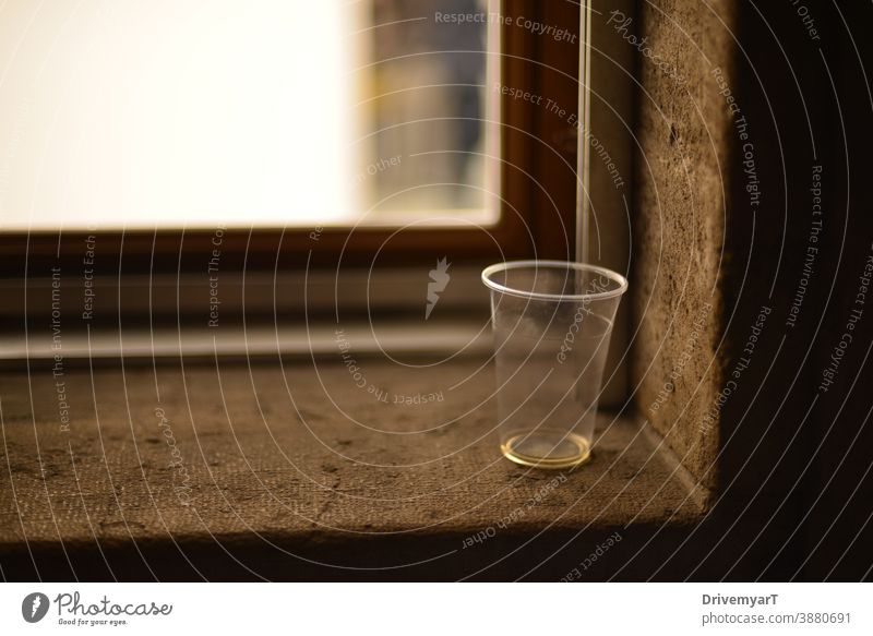 Verlassener leerer Plastikbecher auf einem Fensterbrett Kunststoff Tasse Glas Abfall Verschmutzung durstig Durst Textfreiraum Hintergrund trinken durchsichtig