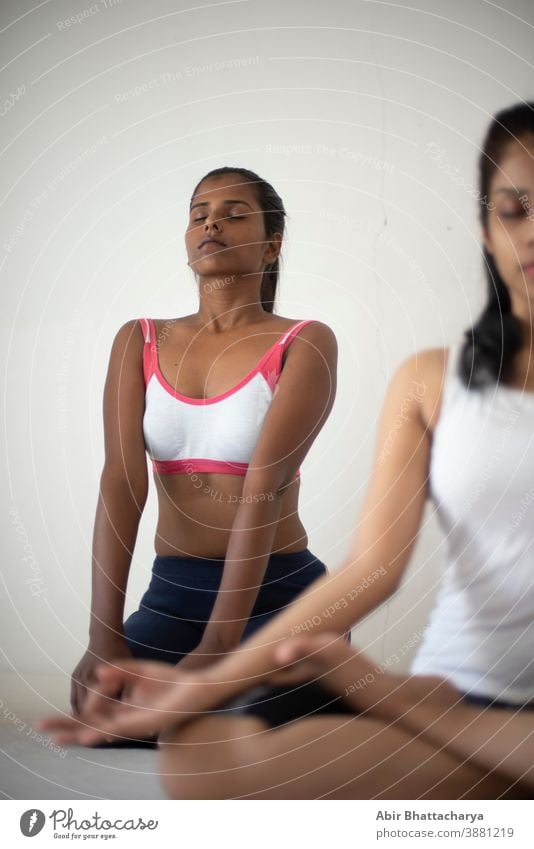 Indische schwarz-weiße brünette Mädchen, die in Unterwäsche vor weißem Hintergrund Yoga/Sport/Übungen machen. Indischer Lebensstil Erwachsener asiatisch