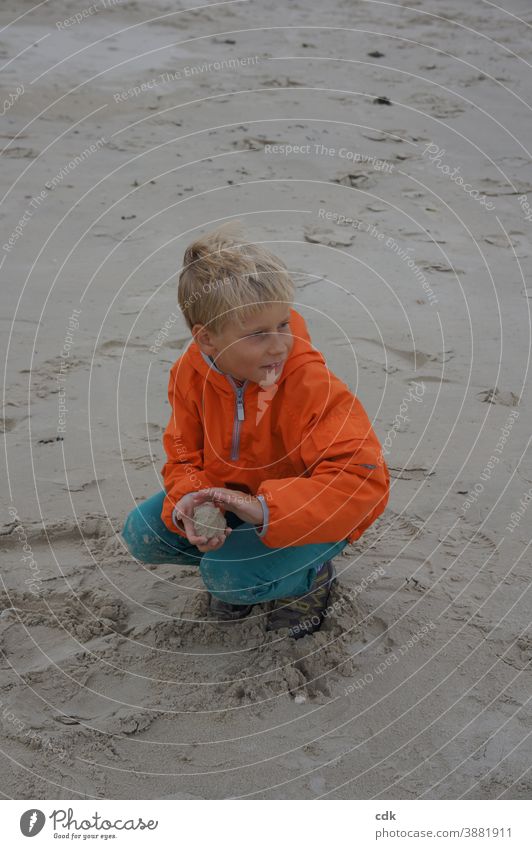 sandige Angelegenheit Junge blond in der Hocke im Sand am Meer orange Windjacke türkis Ferien Sandkugel formend beobachtend