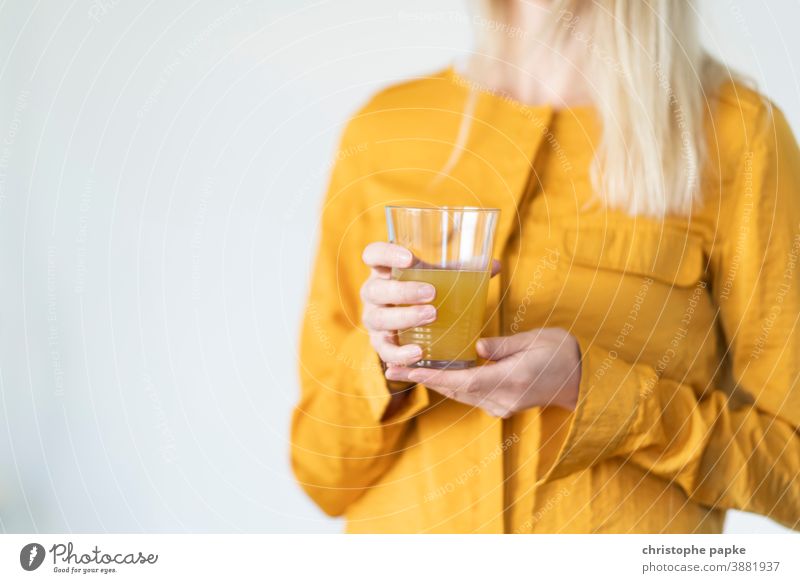 Blonde Frau hält Glas mit Limonade blond Orangensaft trinken Trinkglas halten orange Getränk Saft Erfrischungsgetränk lecker gelb süß Farbfoto Sommer