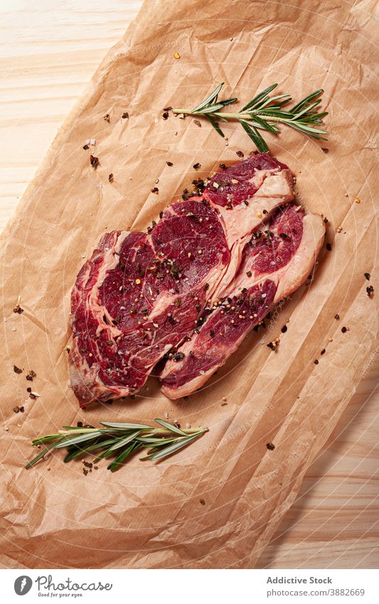 Rindersteak mit Spezies auf Backpapier Steak Rindfleisch roh Fleisch Rippenauge Entrecote Rosmarin Lebensmittel ungekocht Küche Pergament Bestandteil