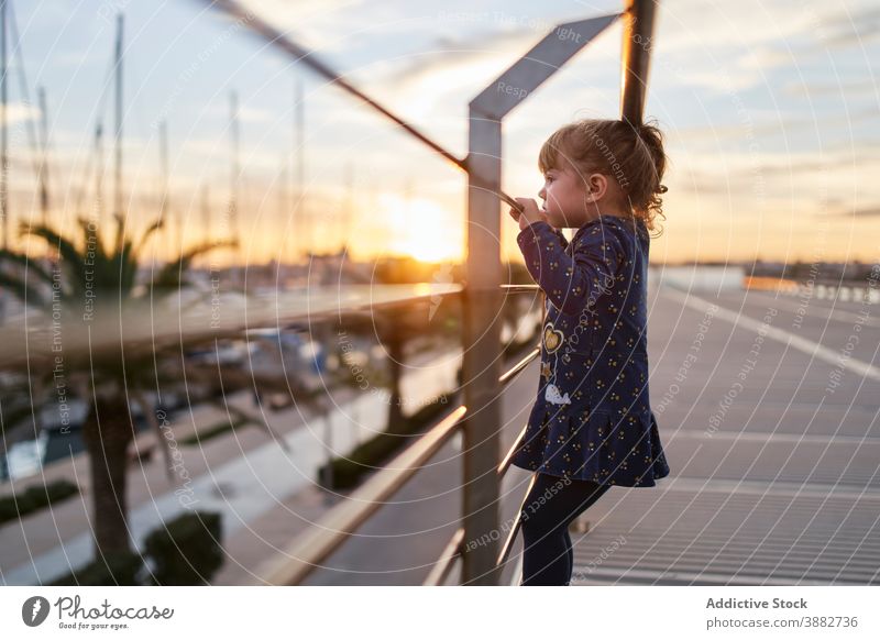 Kleines Mädchen steht auf der Brücke bei Sonnenuntergang Kind neugierig Reling wenig beobachten urban Sommer Abend Lifestyle Kindheit Straße Frau niedlich