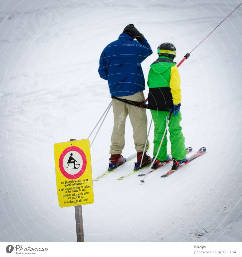 Vater und Kind fahren  Skilift, Schlepplift. Schnee im Skigebiet. Hinweisschild das Schlittenfahrer den Lift nicht benutzen dürfen Skifahrer Skifahren