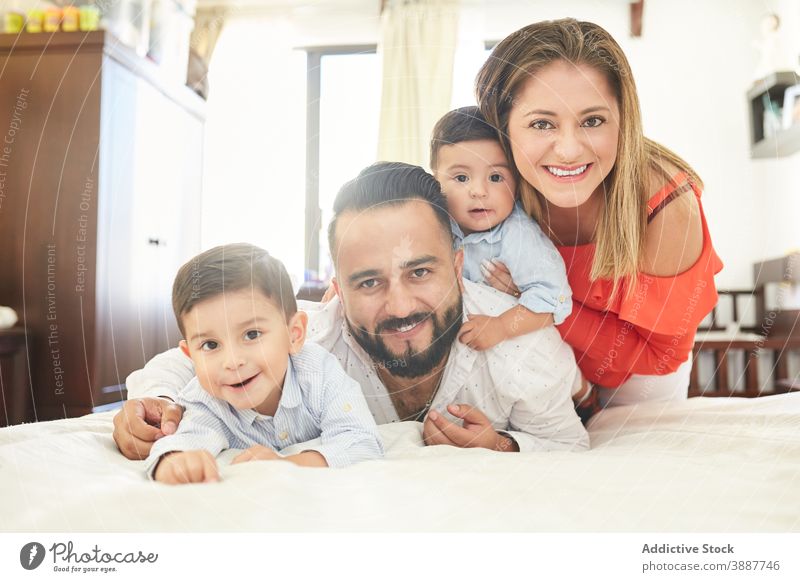Fröhliche ethnische Familie auf dem Bett zu Hause sich[Akk] sammeln Spaß haben Zeitvertreib Zusammensein Paar Sohn Geschwisterkind heimwärts hispanisch