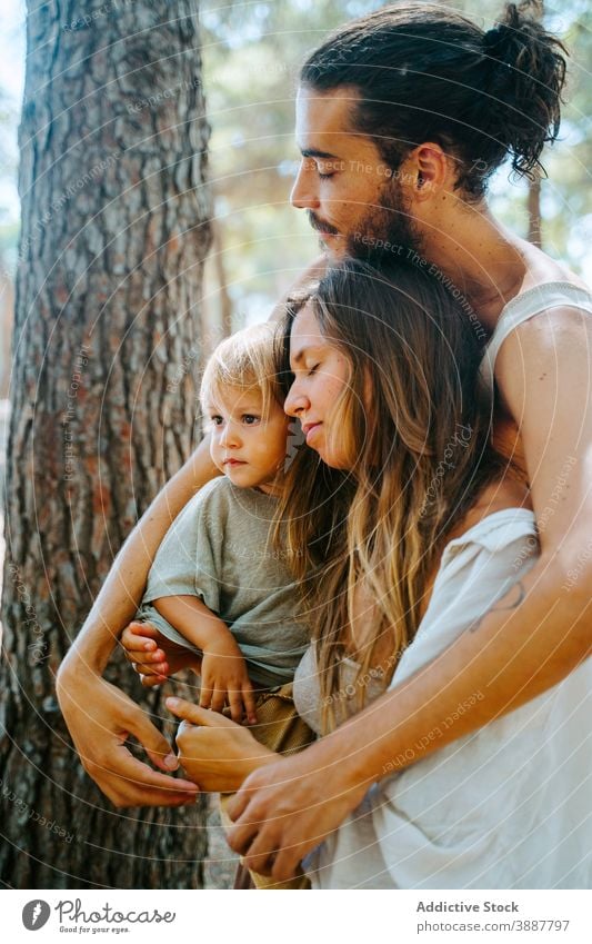 Glückliche multiethnische Familie umarmt mit geschlossenen Augen im Wald Wälder Wochenende Zusammensein Umarmung Kleinkind Kind Liebe Einheit rassenübergreifend