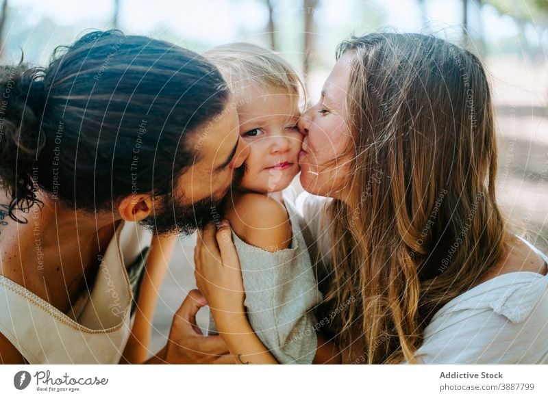 Mutter und Vater küssen Kind zusammen Kuss Familie Wange Liebe kuscheln Zusammensein Einheit multiethnisch rassenübergreifend vielfältig Wald Umarmung Angebot
