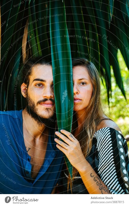 Paar im tropischen Garten schaut in die Kamera Tierhaut Pflanze Blatt Lachen unterhalten multiethnisch rassenübergreifend vielfältig exotisch Park Sommer