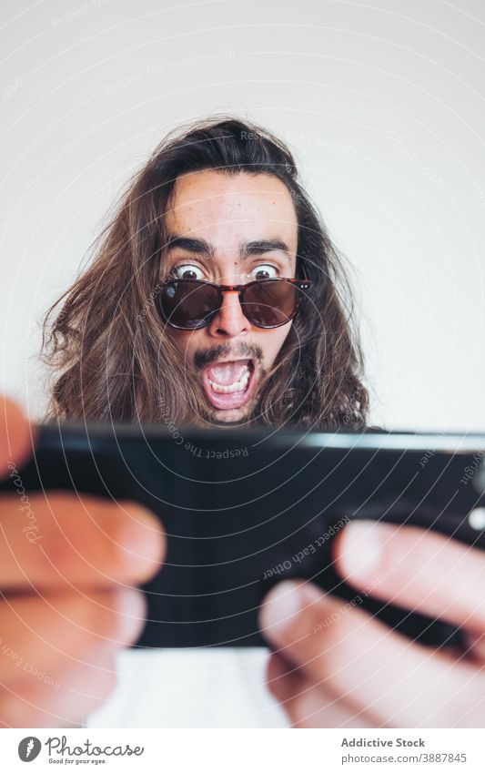Geschockter Mann mit Mobiltelefon Smartphone Schock Erstaunen erstaunt überwältigt Mobile Telefon benutzend zuschauen lesen jung Hipster männlich unglaublich