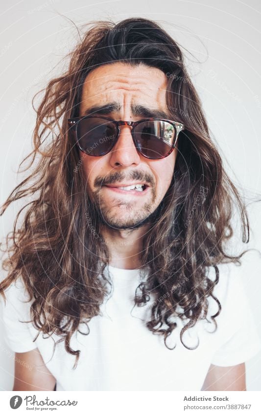 Hipster Mann mit lustigen überraschtes Gesicht Blick auf die Kamera Überraschung erstaunt lange Haare Vollbart Sonnenbrille Menschliches Gesicht expressiv