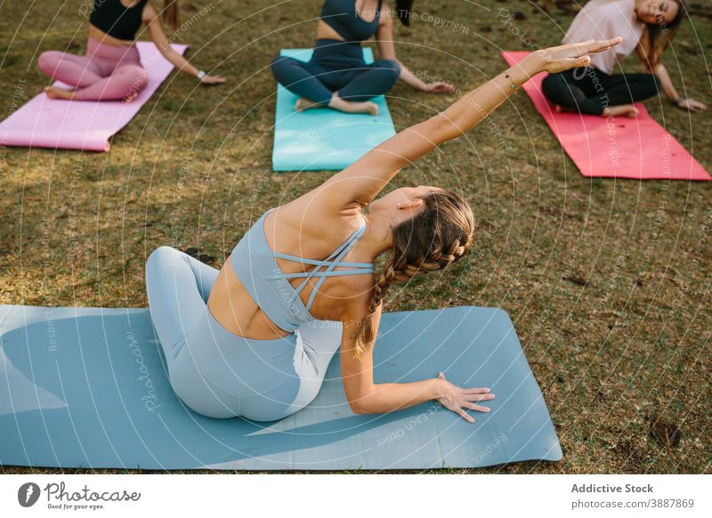 Yogalehrer macht sitzende Seitenbeuge-Pose Ausbilderin Frauen sitzende Seitenkurve sukhasana Park Asana üben Menschengruppe Wellness Lifestyle Harmonie