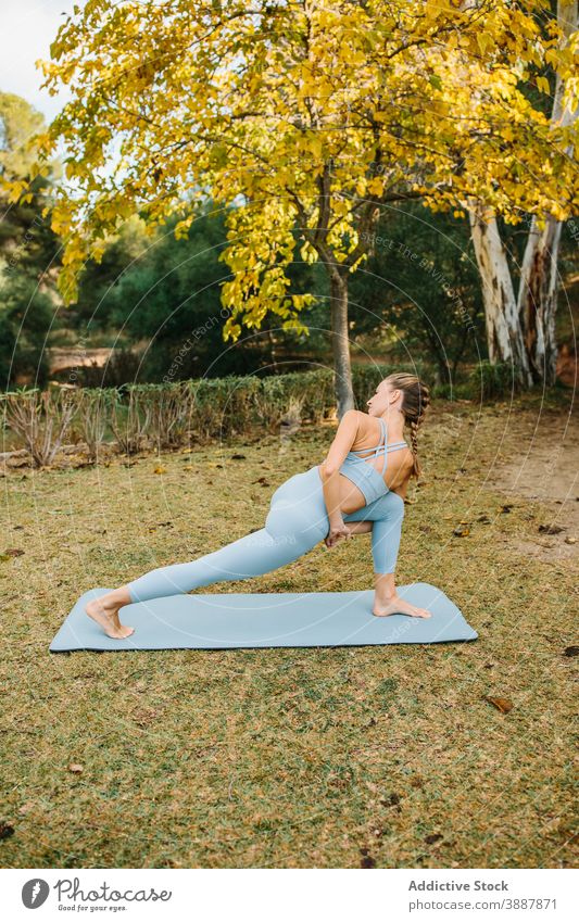 Junge Frau tut verdreht stehenden Yoga-Pose Park gebundene, gedrehte Halbmond-Longe parivrtta baddha anjaneyasana Asana verdrehen Dehnung üben Wellness