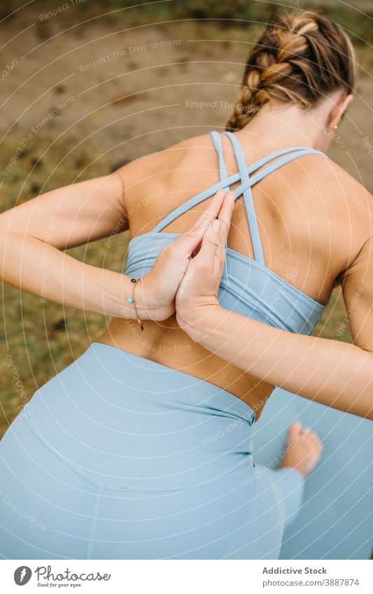 Frau tut Yoga-Pose mit Gebet Hände hinter dem Rücken Park gebundene, gedrehte Halbmond-Longe Halbpyramide Gebetshände ardha parsvottanasana Asana Namaste stehen