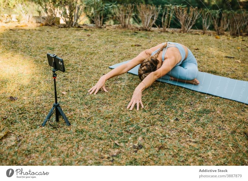 Flexible Frau macht Yoga in Bound Angle Pose Blogger Video Aufzeichnen Smartphone Influencer Randwinkelstellung Asana Mobile Telefon Unterlage Sommer Tutorial