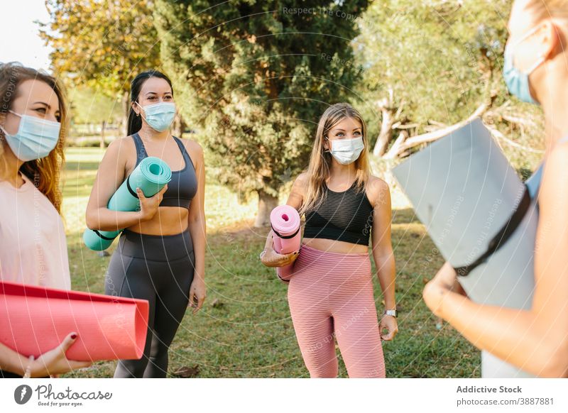 Junge Frauen in Masken bereiten sich auf eine Yogastunde im Park vor Mundschutz Menschengruppe Coronavirus Zusammensein aktiv üben Ausbilderin Pandemie COVID