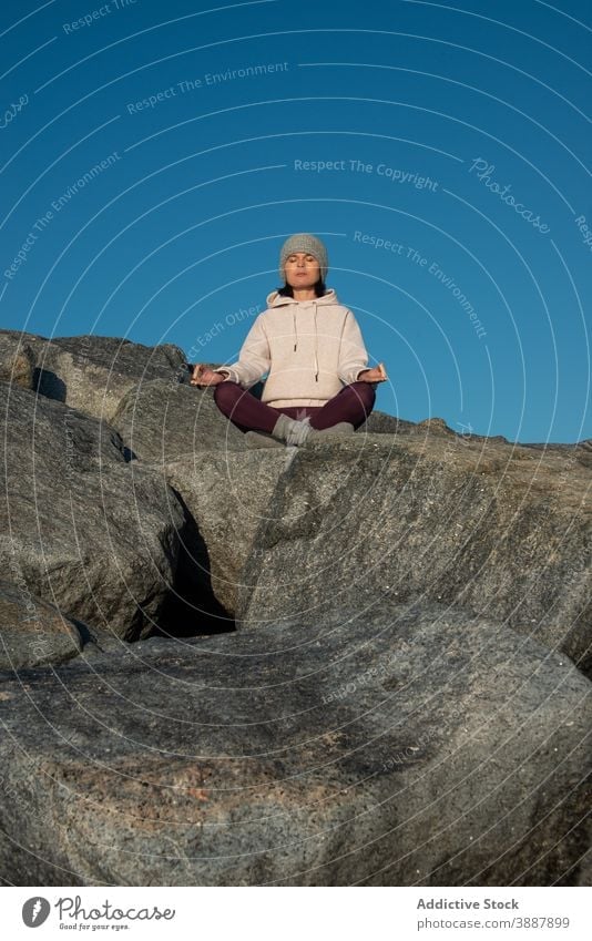 Fokussierte Frau meditiert auf Fels meditieren Yoga Lotus-Pose Mudra sich[Akk] entspannen Stein Felsen Blauer Himmel Natur Achtsamkeit Zen Asana padmasana üben