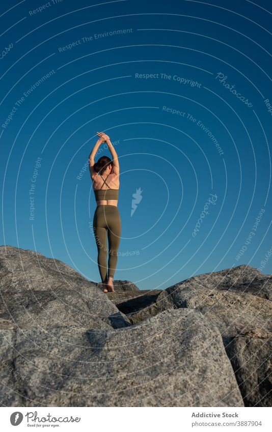 Anonyme fokussierte Frau, die Yoga auf einem Felsen praktiziert sich[Akk] entspannen Stein Blauer Himmel Natur Achtsamkeit Zen üben Wellness Harmonie