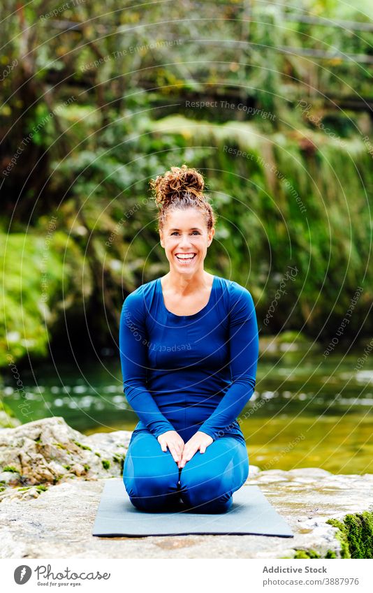 Entzückte Frau beim Yoga in Thunderbolt Asana Donnernde Pose sich[Akk] entspannen See Natur beweglich Vajrasana Zen üben sitzen Glück Wellness Lächeln jung