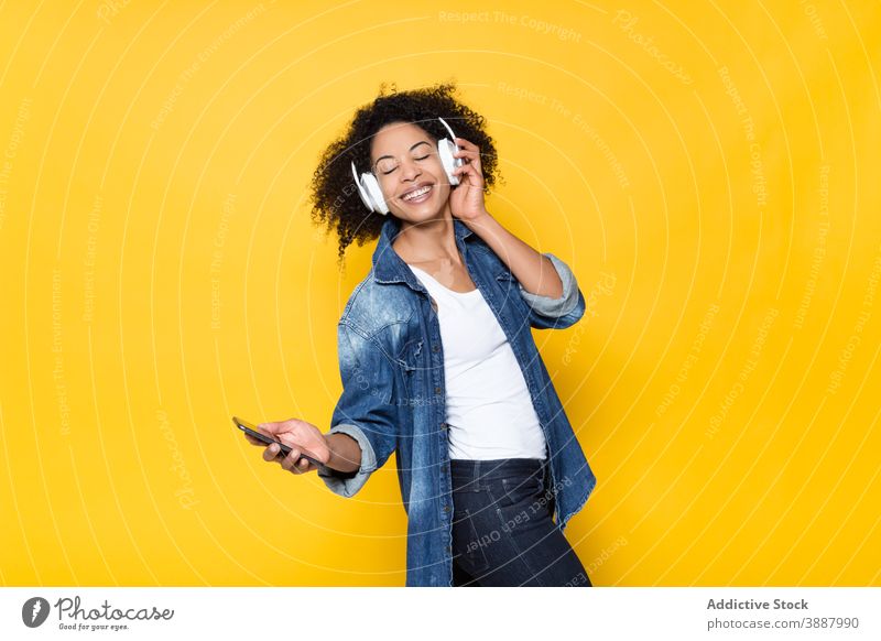 Glückliche schwarze Frau, die mit Kopfhörern Musik hört heiter zuhören Drahtlos Smartphone Spaß haben Hipster genießen jung Afroamerikaner ethnisch Optimist