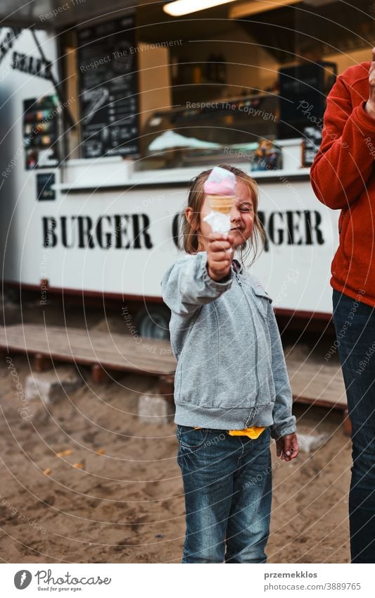 Kleines Mädchen hält sich ihr Eis vor das Gesicht und steht vor einem Speisewagen Menschen Urlaub Familienzeit Familienurlaub Zeit verbringen Ausgaben kaufen
