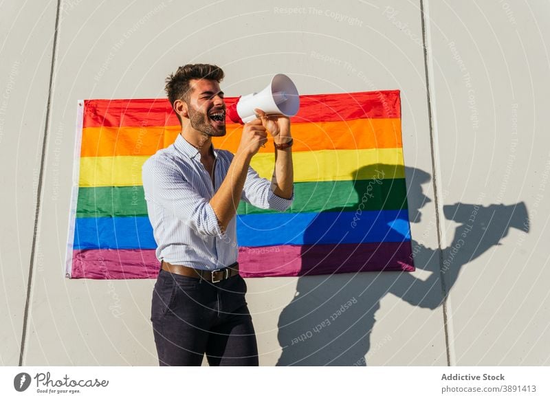 Schwuler Mann schreit in Megaphon auf Straße Lautsprecher schreien Homosexualität lgbt Fahne Regenbogen schwul expressiv männlich lgbtq Stolz Toleranz heiter