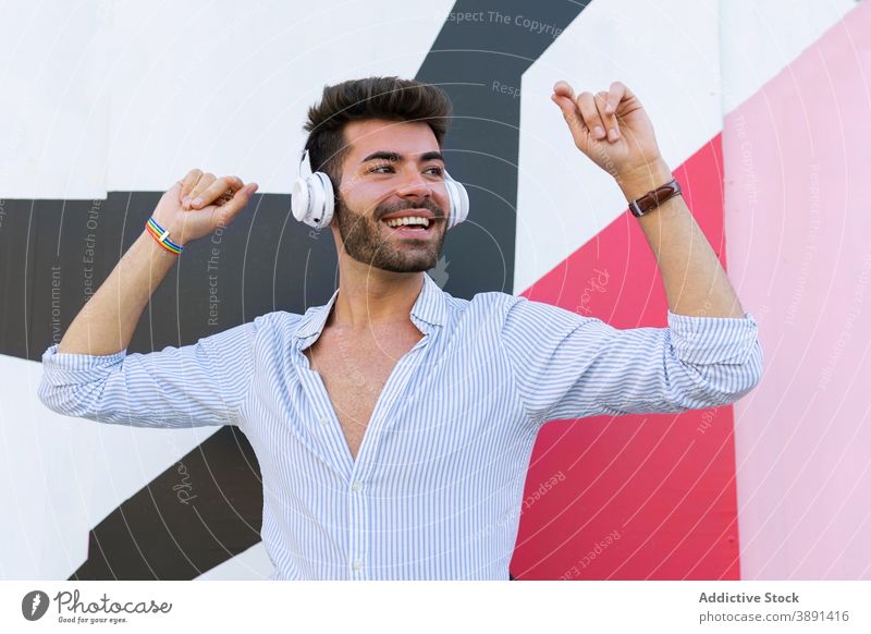 Positiver homosexueller Mann beim Musikhören in der Stadt zuhören Homosexualität schwul lgbt Straße Kopfhörer Gesang Armband männlich sorgenfrei Apparatur Gerät
