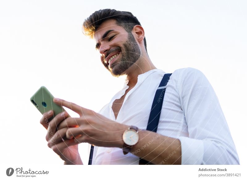 Mann in stilvollem Outfit mit Smartphone in der Stadt Browsen Großstadt Straße Nachricht Stil trendy gutaussehend Lächeln männlich Mobile Telefon Kommunizieren